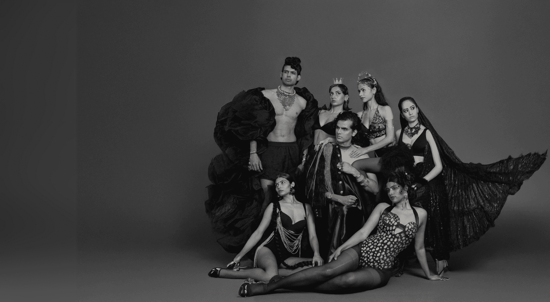 Honepage Banner A striking high-fashion editorial group portrait showcasing six models in avant-garde black ensembles with luxurious gold accents